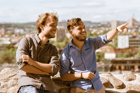 Young man showing something interesting to his friend as travel and friendship conceptの写真素材