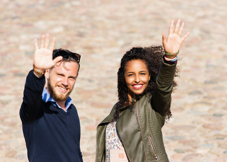 Young multiracial couple greeting their friends as diversity friendship and togetherness conceptの写真素材