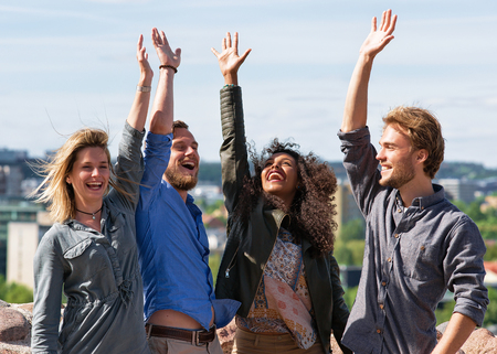 Group of young smiling friends raising their hands up Concept