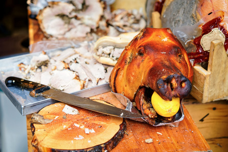Traditional italian pork cut into slices. With pig head with lemon as a decoration, Rome, Italyの写真素材