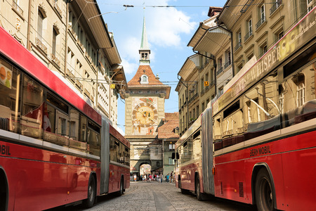 Bern, Switzerland - August 31, 2016: Two running red city buses on Kramgasse street at Zytglogge...