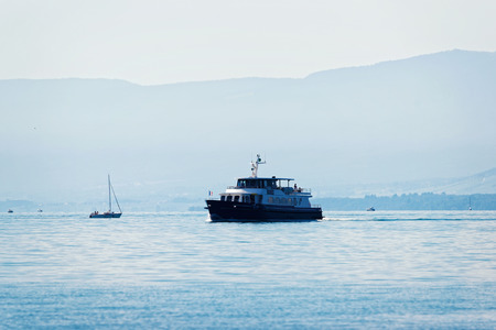 Excursion ferry with Swiss flag on Lake Geneva at Ouchy embankment in Lausanne, Switzerland. People aboardの写真素材