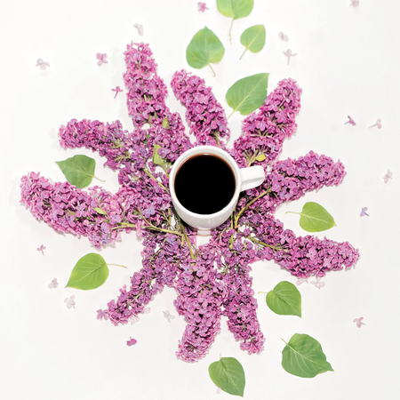 Cup of coffee and violet lilac flowers on the white background. Flat lay, top viewの写真素材
