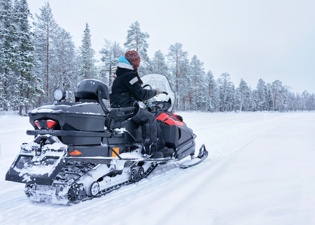 Woman riding snowmobile on the frozen lake at winter Rovaniemi, Lapland in Finlandの写真素材