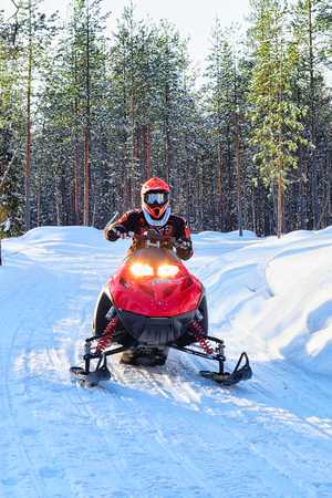 Rovaniemi, Finland - March 5, 2017: Woman riding red snowmobile on the frozen lake at winter Rovaniemi, Lapland in Finlandのeditorial素材