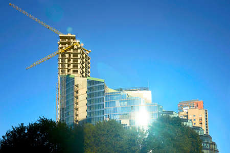 Development of modern steel and glass futuristic forum skyscraper reflecting in the blue sky.の写真素材