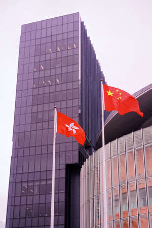Hong Kong flag and Flag of China during the fog. Skyscrapers on the background, Hong Kong downtownのeditorial素材
