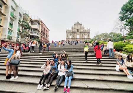 Macao, China - March 8, 2016: Friends making selfie photos at Ruins of Saint Paul Church in Historical old city center in Macao, China. People on the backgroundのeditorial素材