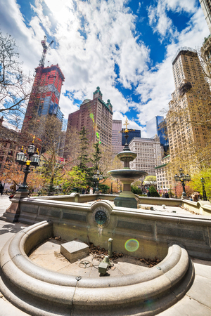 New York, USA - April 24, 2015: Fountain and Skyscrapers in City Hall Park in Lower Manhattan, New York, NYC, USA. Skyscrapers and tourists on the background. With sun flareのeditorial素材