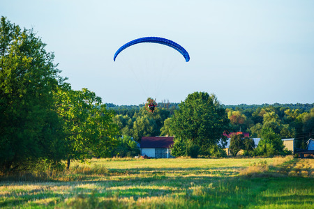 Paraglider flies with the parachute in the countryside of Poland