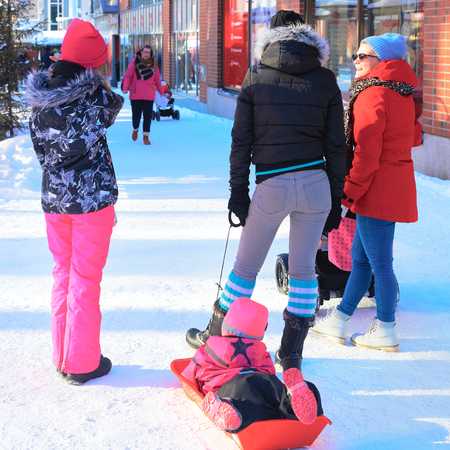 Rovaniemi, Finland - March 4, 2017: Women with child on toboggan in the street of winter Rovaniemi, Finland.のeditorial素材