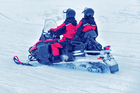 Couple riding a snowmobile on the frozen lake in winter Rovaniemi, Lapland, Finlandの写真素材