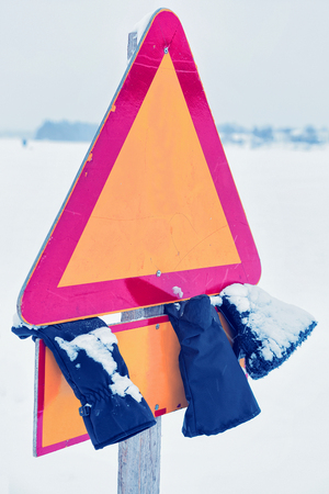 Road sign and lost gloves in the street in winter Rovaniemi, Lapland, Finland.の写真素材