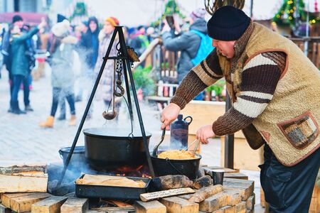 Riga, Latvia - December 29, 2016: Trader cooking hot wine for selling at Christmas Market at Dome...