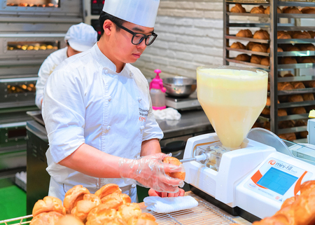 Busan, South Korea - March 13, 2016: Pastryman putting cream into the puffs in the food corner at the shopping mall in Busan, South Koreaのeditorial素材