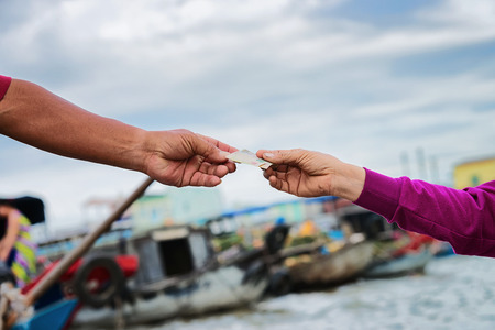 The moment of purchase and exchange of money for the goods at the Floating market at the delta Mekong in Can Tho, Vietnamの写真素材