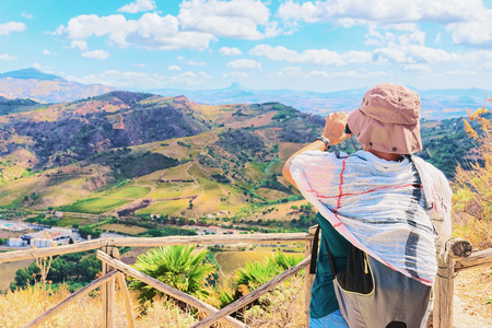 Woman taking photos of the scenery of Segesta at the Greek Theater in Sicily, Italyの写真素材