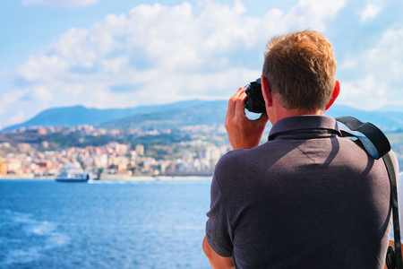 Man taking photos of the Mediterranean Sea and landscape in Reggio Calabria, Italyの写真素材