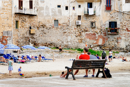 Cefalu, Italy - September 26, 2017: Seaside with people sitting on the benches in Cefalu old town, Palermo region, Sicily island, in Italyのeditorial素材