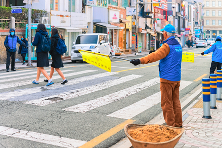 Busan, South Korea - March 14, 2016: Traffic controller helping children to cross the street in the city center of Busan in the morning, South Koreaのeditorial素材