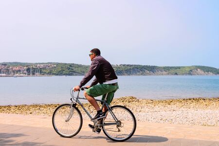 Izola, Slovenia - April 24, 2018: Man riding a bicycle at the embankment of the Adriatic Sea in Izola fishing village, Sloveniaのeditorial素材