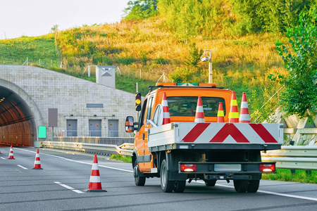 Truck carrying trailer with road safety cones on the asphalt road of Slovenia.