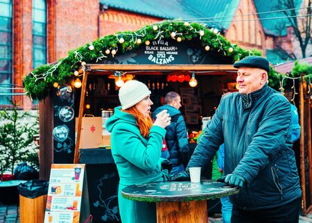 Riga, Latvia - December 28, 2016: Couple drinking mulled wine at Christmas market in Riga in Latvia in winter.のeditorial素材