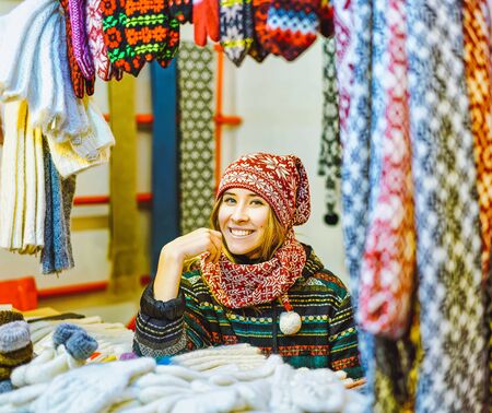Riga, Latvia - December 24, 2015: Girl selling knitted clothes on stalls at Christmas market in Riga in Latvia in winter.のeditorial素材