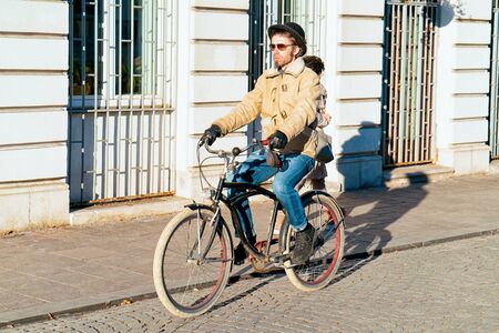 Ljubljana, Slovenia - January 15, 2019: Man hipster riding bicycle in street and cityscape of Ljubljana old town, Slovenia. People on bike and cycle in Slovenian city view in winter. Cyclist and roadのeditorial素材