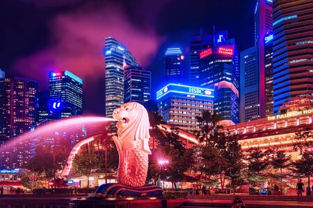 Singapore, Singapore - March 1, 2016: Merlion statue sprays the water from its mouth at Merlion Park in Downtown Core of Singapore at Marina Bay at night. Skyline with Skyscrapers on backgroundのeditorial素材
