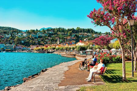 Ascona, Switzerland - August 23, 2016: Senior people sitting on bench in Ascona luxury tourist resort on Lake Maggiore in Ticino canton in Switzerland in summer. People outdoor street travel.のeditorial素材