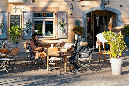 Ljubljana, Slovenia - January 15, 2019: Young women eating and drinking in restaurants, tables and chairs in Ljubljana old town embankment, Slovenia. Ladies in open air cafes in Slovenian capital cityのeditorial素材