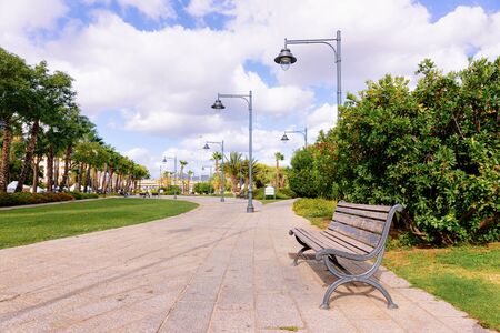 Bench at Parco Giardinetti Park in Old city of Olbia on Sardinia Island in Italy. Italian coast of Sardegna. Sky with romantic cloudsの写真素材