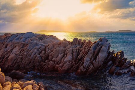 Romantic sunrise on Capriccioli Beach of Sardinia island in Italy. Sky with clouds. Stones and rocks.の写真素材