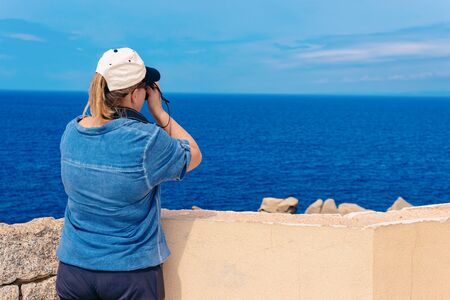 Woman with camera at rocks in Capo Testa at the Mediterranean sea in Santa Teresa Gallura province in Sardinia island in Italy. Scenery with person in Sardegna.の写真素材