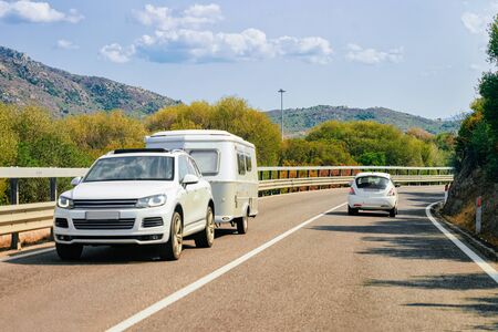 Rv cavaran and car on the road in Sardinia Island in Italy in summer. Motorhome rving on motorway. Camper trailer on highway.の写真素材