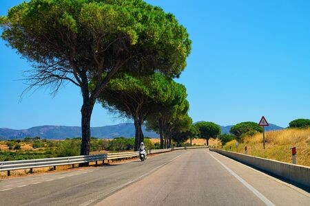 Motorcycle at the road in Sardinia in Italy in summer. Motorcyclist driving scooter on the highway in Europe. View on moped on motorway.の写真素材