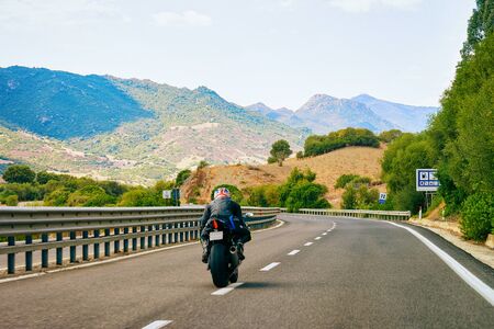 Motorcycle at the road in Costa Smeralda in Sardinia Island in Italy in summer. Motorcyclist driving scooter on the highway in Europe. View on moped on motorway.の写真素材