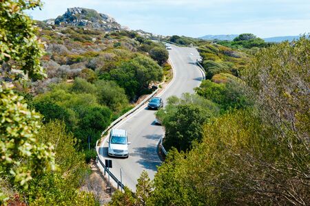 Cars with driving at the highway road at Capo Testa in Santa Teresa Gallura at the Mediterranean Sea on Sardinia Island in Summer Italy. Holiday adventure in mountains.の写真素材