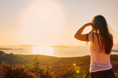Sunrise or sunset and young girl in Porto Rotondo at the Mediterranean sea in Sardinia island in Italy. Boat in Sardegna in summer.の写真素材