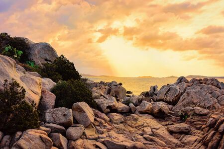 Romantic sunrise at Capriccioli Beach at Sardinia island in Italy. Sky with clouds. Stones and rocks.の写真素材