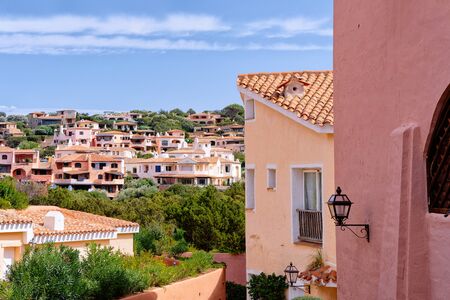 View on of residential house complex. Apartment flat building. Coastal home architecture in Porto Cervo luxury resort city in Sardinia Island in Italy in summer. View on Sardinian town in Sardegna.の写真素材