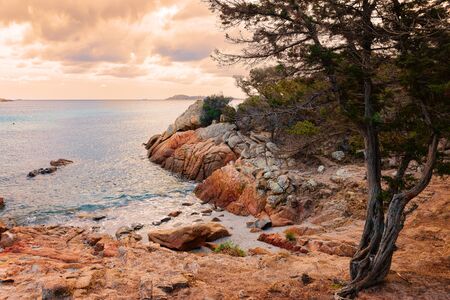 Romantic sunrise on Capriccioli Beach on Sardinia island in Italy. Sky with clouds. Stones and...