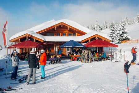 Mayrhofen, Austria - February 4, 2019: People at street cafes with tables in Zillertal Arena ski resort in Tyrol in Austria in winter in Alps. Skiers eating and drinking at restaurant.のeditorial素材