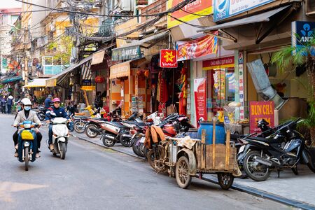 Hanoi, Vietnam - February 21, 2016: Local people riding mopeds on street of old city of Hanoi in Vietnam in Southeast Asia. Locals on motorcycles on road. Traffic with motorbikes.のeditorial素材