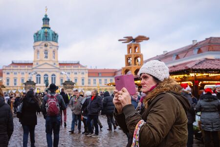 Berlin, Germany - December 9, 2017: Senior woman making selfie at Christmas market in Charlottenburg in Berlin in Germany in Europe in winter. German street Xmas and holiday fairのeditorial素材