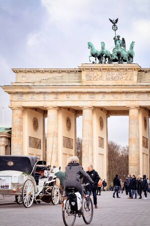 Berlin, Germany - December 8, 2017: Person on bicycle at Brandenburg gate in Berlin in Germany in Europe in winter. Brandenburger Tor, panorama of German European city wall in December.のeditorial素材