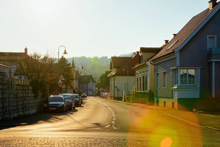 Cottage townhouse residential apartment and flat building exterior in Leibnitz, Austria. Street with New luxury house and home complex. City architecture. Car parked on street. Sun flare at sunsetの写真素材