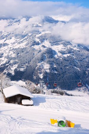 Chalet, artificial snow making canon and Red Cable cars in Zillertal Arena ski resort in Tyrol in Mayrhofen in Austria in winter Alps. Chair lifts in Alpine mountains. Downhill fun at snowy slopes.の写真素材