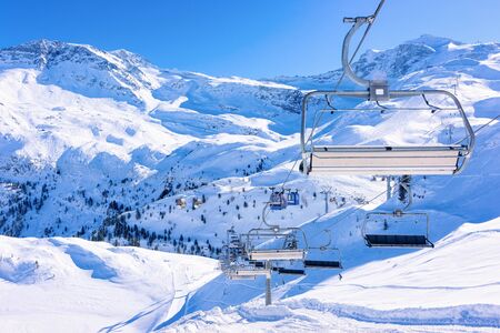 Cable cars in Hintertuxer Gletscher in Alpine mountains with white snow and blue sky.